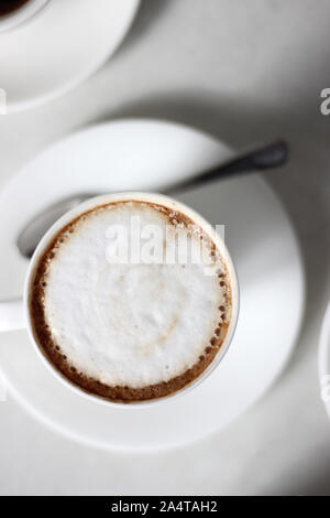 Freshly Brewed Cappuccino in demitasse cup. Overhead Closeup view of Coffee isolated on a white background. Stock Photo