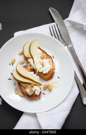 Overhead view of Crostini with Ricotta Cheese, Pear Slices and Peanuts. Healthy Breakfast Food. Stock Photo