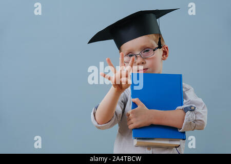 Redhead first grader boy in glasses and student hat showing four fingers Stock Photo