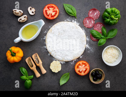 The ingredients for homemade pizza on dark stone background. Stock Photo