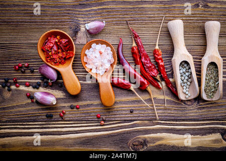 Various herbs and spices in wooden spoons on wooden background. Stock Photo