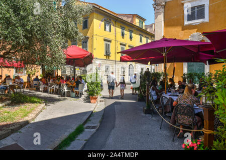 Street view of the historic centre of the famous town of Pisa with outdoor restaurants full of people and tourists lunching in summer, Tuscany, Italy Stock Photo