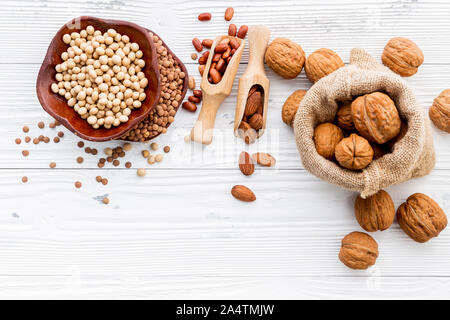 Various legumes and different kinds of nuts set up on white wooden table. Stock Photo