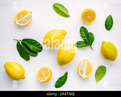 Fresh lemons and  lemons leaves on white wooden background. Stock Photo