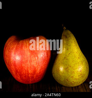 Group of fresh fruits consisting of apple and pear on a rustic wooden table with black background. Stock Photo
