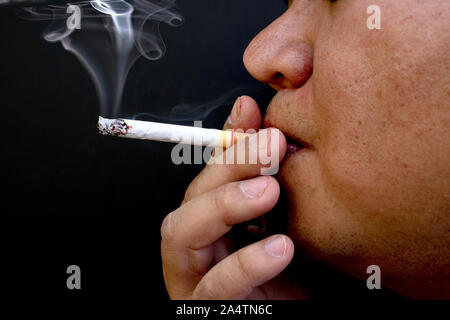 Man smoking a cigarette, Image of cigarette in hand with smoke Stock Photo