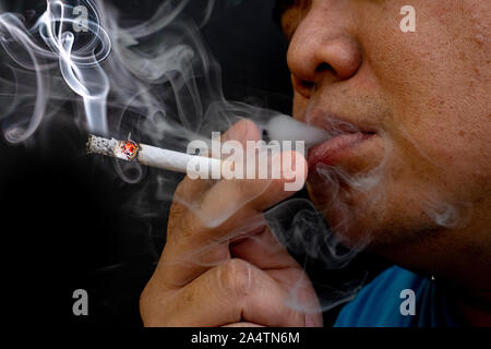 Man smoking a cigarette, Image of cigarette in hand with smoke Stock Photo