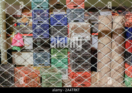 Storage plastic container crates stacked in market. Night view of colorful multipurpose crates stack behind store security shutter gate, Kapani Market Stock Photo