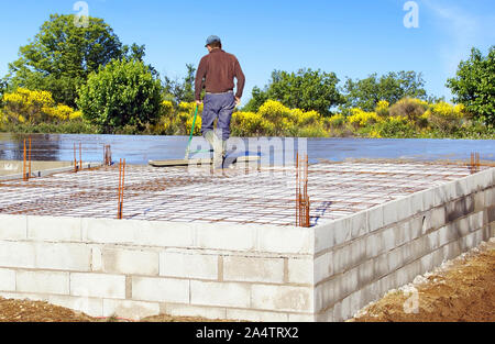 Distribution of concrete for the realization of the floor of a house under construction. Stock Photo