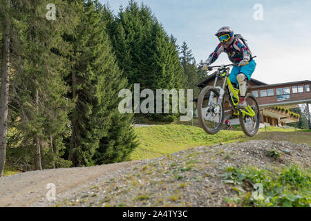 Lenzerheide, GR / Switzerland, - 12 October, 2019: downhill mountain biker jumping high and riding hard in Lenzerheide in the Swiss Alps Stock Photo