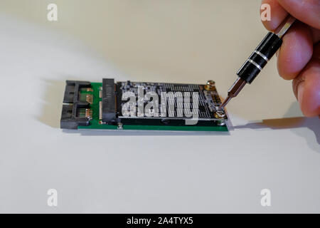 Human hand working on ssd chipset replace computer components with screwdriver Stock Photo