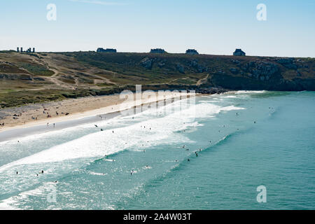 A view of the Plage de Pen Hat beach and bay with many surfers surfing on  a beautiful summer day on the coast of Brittany Stock Photo