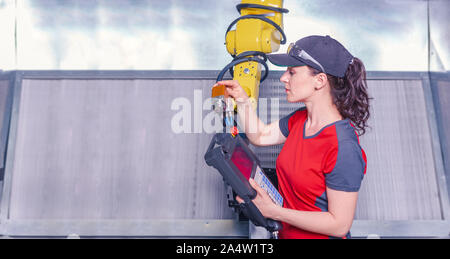 A young female technician while machine constructing in a manufacturing plant Stock Photo