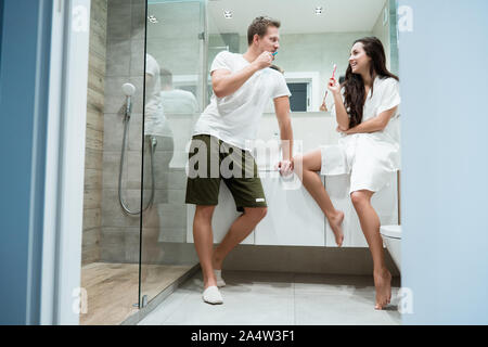 young handsome man and beautiful woman brushing teeth in bathroom Stock Photo