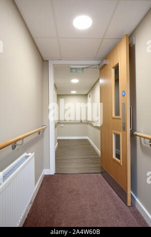 Access corridor in a newly refurbished care home near Wakefield, UK. Shows safety handrails and fire door. Stock Photo