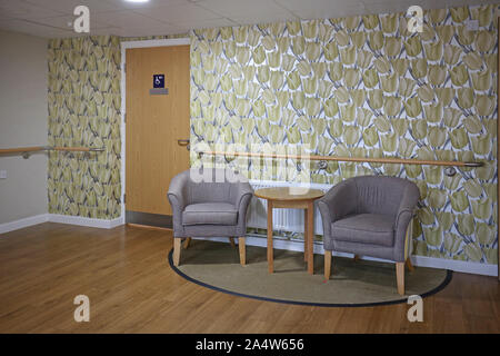 Interior of a newly refurbished care home near Wakefield, UK. Shows corridor seating area with bright wallpaper, armchairs and safety handrails. Stock Photo