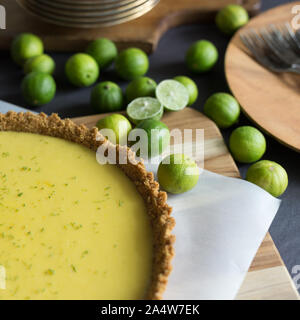 Homemade Key lime pie shown on parchment paper, shown with extra key limes. Stock Photo