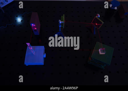 Experiment in optic lab with laser device. Red laser on optical table in physics laboratory Stock Photo