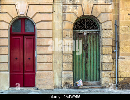 Two vintage arched doors. Old fashioned red door and run-down green door. Retro entry doors in Valletta, Malta. Stock Photo