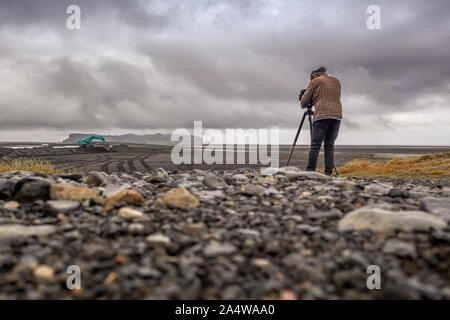 Filmmaker taking videos, Hjorleifshofdi, South Coast, Iceland Stock Photo