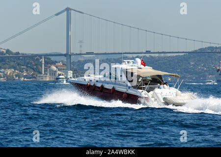 Power boat taxi in Bosphorus Strait moving fast and splashing water. Anatolian Site of Istanbul and Bosporus Bridge in the background. Stock Photo