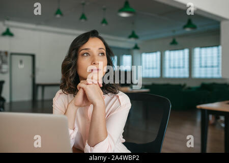 Young businesswoman sitting at her office desk thinking about work Stock Photo