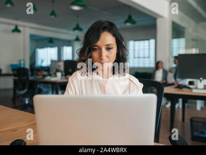 Focused young businesswoman working on her laptop in an office Stock Photo