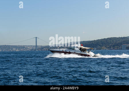 Power boat taxi in Bosphorus Strait moving fast and splashing water. Anatolian Site of Istanbul and Bosporus Bridge in the background. Stock Photo