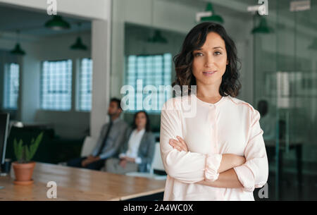 Smiling young businesswoman standing confidently in a large office Stock Photo
