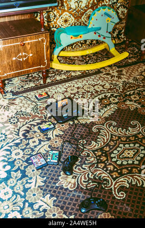 KHARKIV, UKRAINE MAY 28, 2017: Vintage room, old-fashioned carpet, retro TV, sega, game console, 90s collectible bottles and standard wooden cabinet. Stock Photo