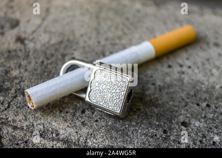 The ban on smoking cigarettes in public places. Cigarette and lock on concrete Stock Photo