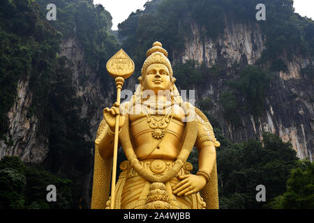 Gombak, Selangor, Malaysia 08.14.2019: Upper body part of the giant and amazing golden Murugan statue with the famous limestone hill of Batu Caves in Stock Photo