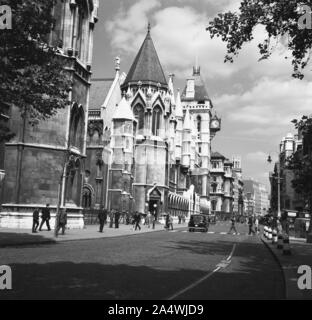 1950s, historical, view from this era of the Strand and the soot-covered Royal Courts of Justice, City of Westminster, London, England, UK. The buildings, a complex of courtrooms, halls and offices overseeing the justice involving civil litigation are Victorian gothic in style. Designed by English Architect, George Edmund Street, noted for his many churches in the Gothic revival architectural style, the courts, located on the Strand on the edge of the City of London, were opened in 1882. Stock Photo