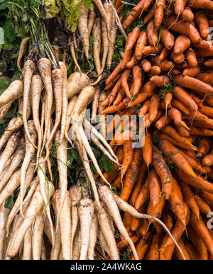 Raw and unwashed  parsnips and carrots for sale at a supermarket, raw food background textures Stock Photo