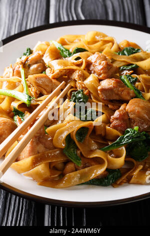 Thai Pad See Ew noodles with chicken, Chinese broccoli and egg close-up on a plate on the table. vertical Stock Photo