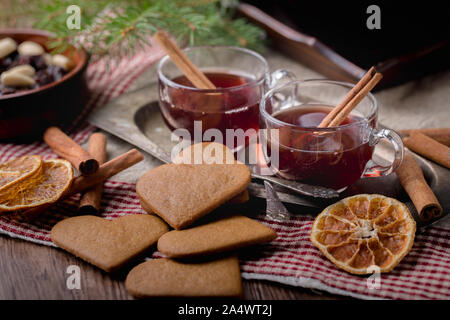 Mulled wine with cinnamon sticks, known as  glögg in Sweden. The glasses are on an old metal tray surronded by heart shaped traditional swedish ginger Stock Photo