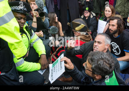 London, UK. 16 October, 2019. A Metropolitan Police officers prepare to arrest Jonathan Bartley (c), co-leader of the Green Party, Guardian journalist George Monbiot (r) and a group of climate activists from Extinction Rebellion using Section 14 of the Public Order Act 1986 after they sat in the road in Whitehall following a People’s Assembly in Trafalgar Square as part of a protest against the use by the Metropolitan Police of Section 14 so as to prohibit entirely Extinction Rebellion Autumn Uprising protests throughout the capital. Credit: Mark Kerrison/Alamy Live News Stock Photo