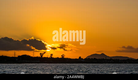 Longniddry Bents, East Lothian, Scotland, United Kingdom, 16th October 2019. UK Weather: Orange sunset looking towards Edinburgh and the hump of Arthur's Seat across the Firth of Forth Stock Photo