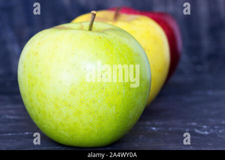 Green ,yellow and red apples on a dark wooden base Stock Photo