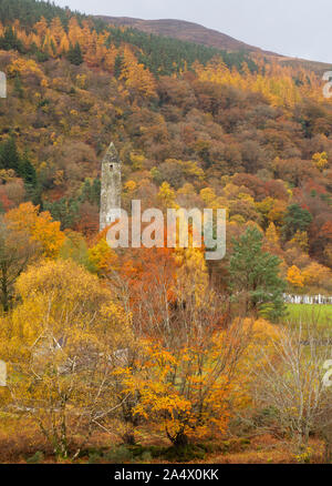 The Round Tower amidst trees in full Autumn colour, Glendalough, Wicklow Mountains National Park, County Wicklow, Ireland Stock Photo