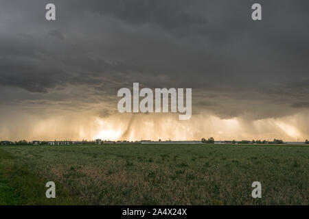 Thunderstorm with menacing clouds and rain streaks, backlit by the sun Stock Photo