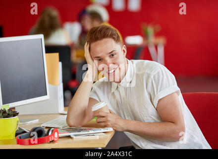 Confident male designer having a coffee at work in red creative Stock Photo