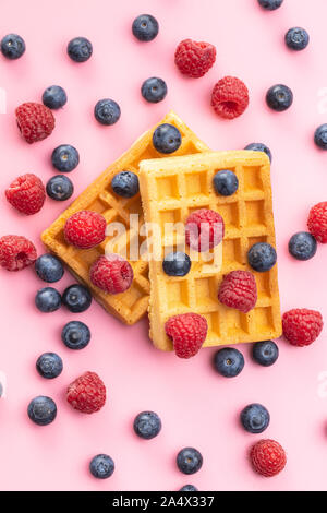 Waffles with blueberries and raspberries on pink background. Stock Photo
