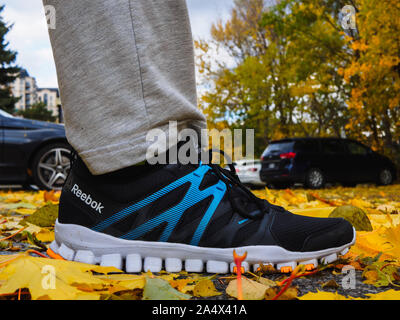 Reebok RealFlex 4 running shoes stepping around yellow leaves on the ground in autumn. Stock Photo