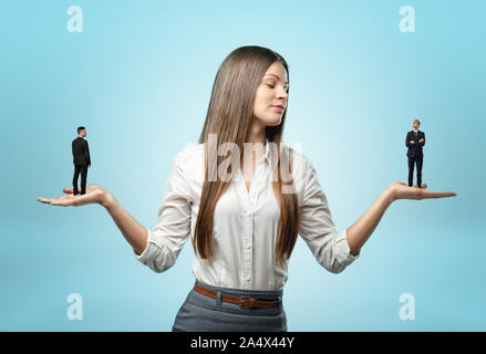 Woman holding small-scale businessman on each outstreched hand Stock Photo