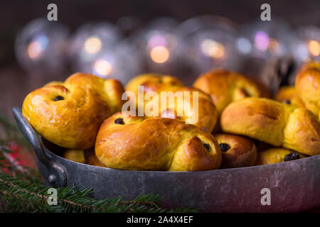 A tray of freshly baked homemade Swedish traditional saffron buns, also known as lussekatter or lussebullar. The yellow buns have raisins and are shap Stock Photo