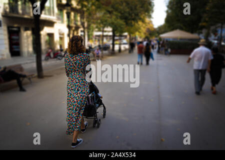Mother with baby carriage on La Rambla street of Barcelona ,seen from behind Stock Photo