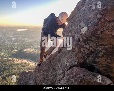 Man climbs freesolo on steep ridge shortly after sunrise Stock Photo