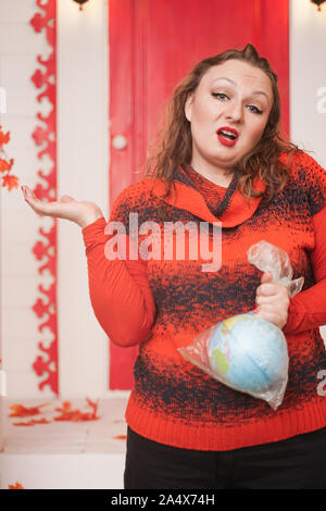 an emotional adult woman holds a planet in a plastic bag in her hands and shows irresponsible excessive consumer plastic. Stock Photo