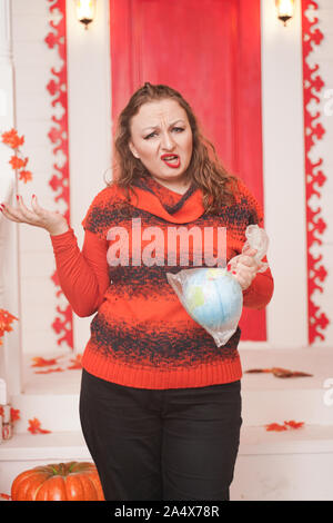 an emotional adult woman holds a planet in a plastic bag in her hands and shows irresponsible excessive consumer plastic. Stock Photo